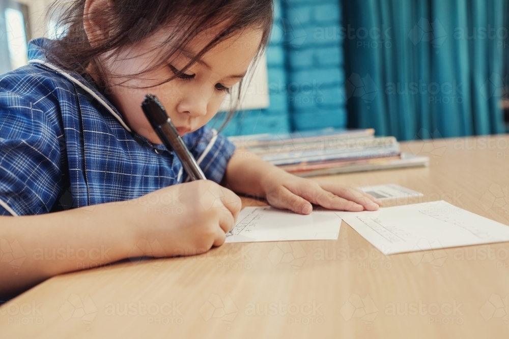 Young student girl writing in libary - Australian Stock Image