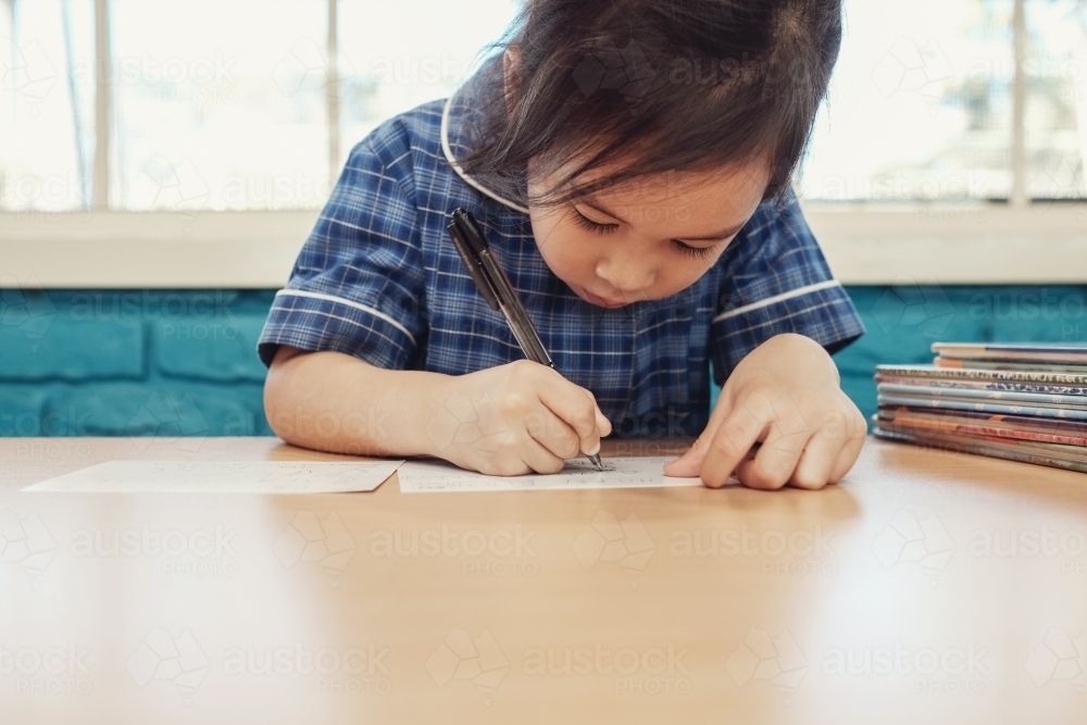 Young student girl writing in libary - Australian Stock Image