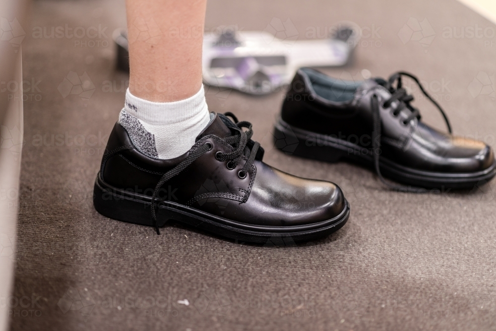 young teen trying on new school shoes - Australian Stock Image