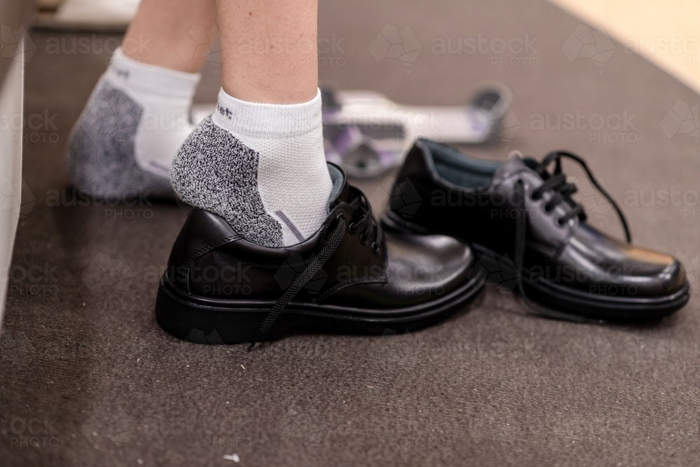 young teen trying on new school shoes - Australian Stock Image