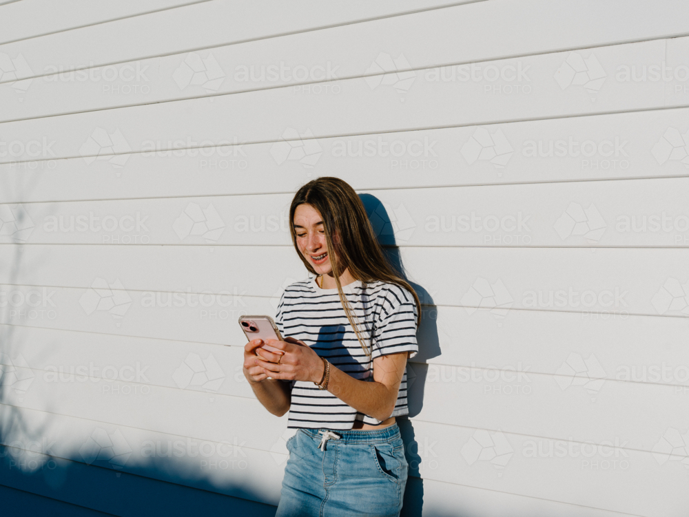 Young teenage girl holding a mobile device. - Australian Stock Image