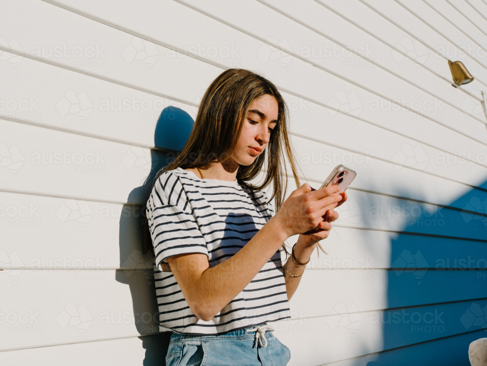 Young teenage girl holding a mobile device. - Australian Stock Image