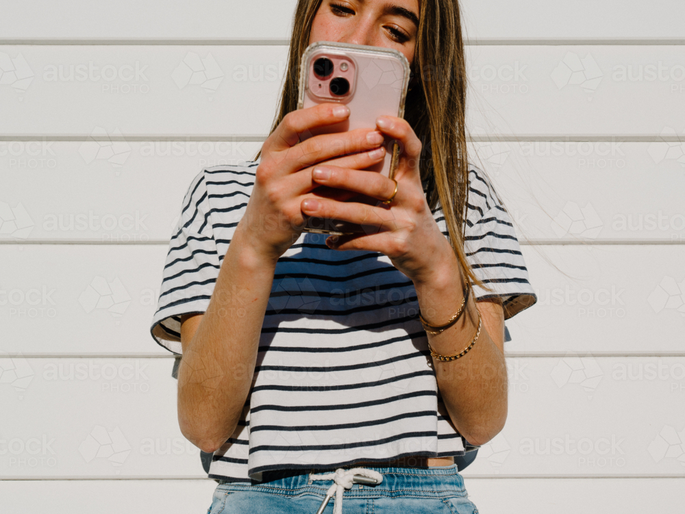 Young teenage girl holding a mobile device. - Australian Stock Image