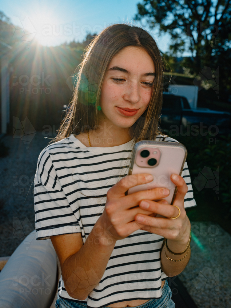 Young teenage girl holding a mobile device. - Australian Stock Image