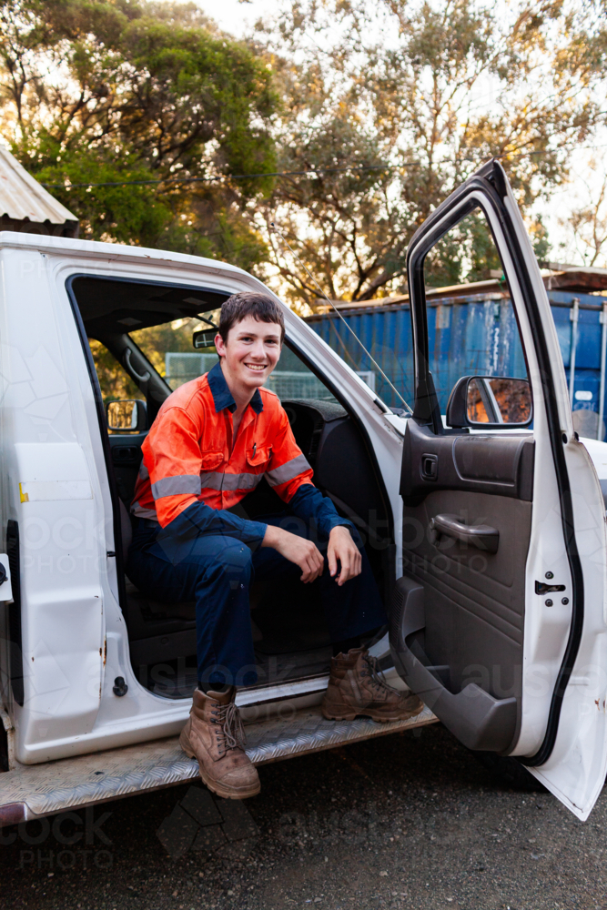 Young Teenaged Australian bloke in high-vis workwear sitting in drivers seat of ute on farm - Australian Stock Image