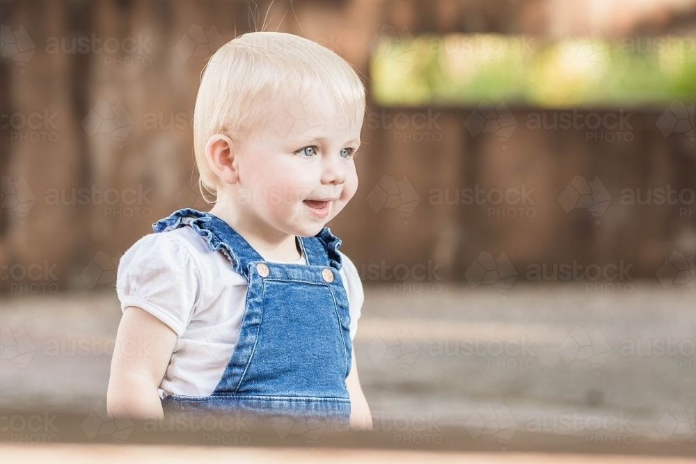 Young toddler girl smiling playing in garden - Australian Stock Image