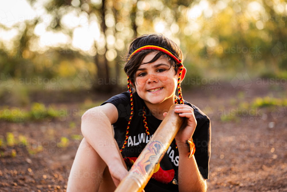 Young tween First Nations Australian boy outside in rural Australia holding didgeridoo - Australian Stock Image