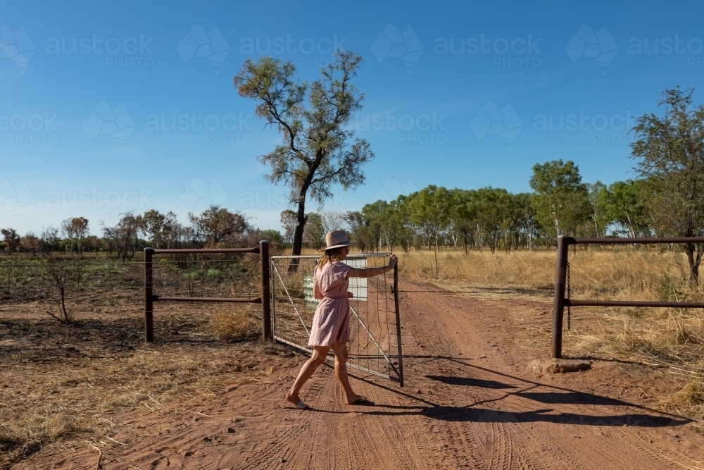 young woman closing gate on outback station - Australian Stock Image