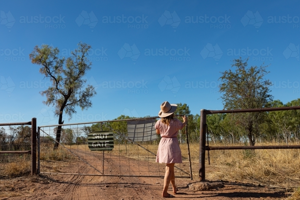 Image of young woman closing gate on outback station Austockphoto