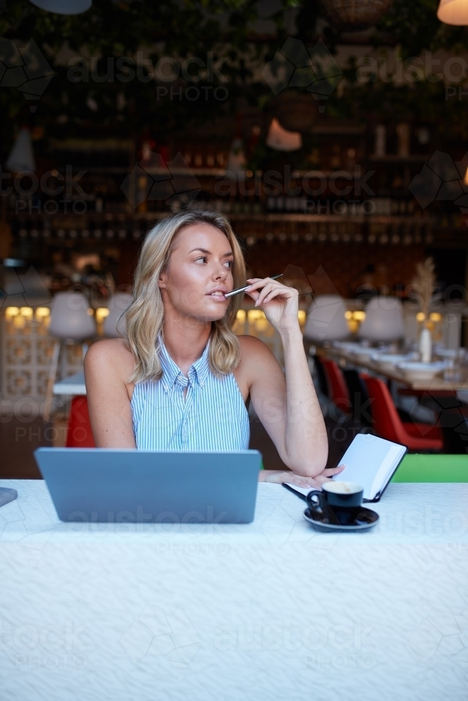 Young woman freelancing from her laptop at cafe - Australian Stock Image