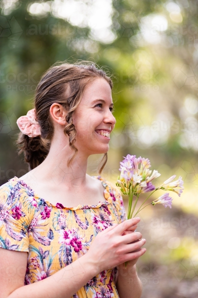 young woman holding a posy of freesia flowers picked in bushland - Australian Stock Image