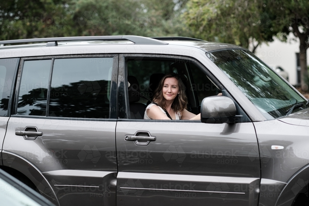 Young woman in 4wd vehicle looking out the window while parking - Australian Stock Image