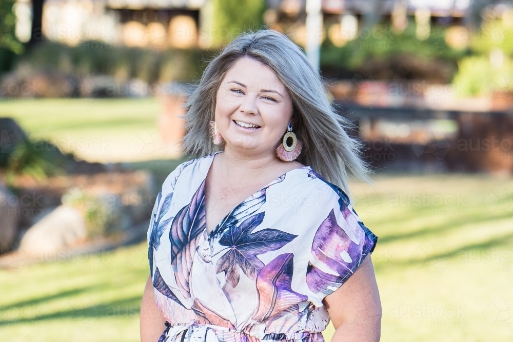 Young woman in early 20s in garden smiling - Australian Stock Image