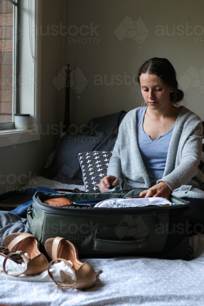 Young woman packing her bag ready to travel - Australian Stock Image