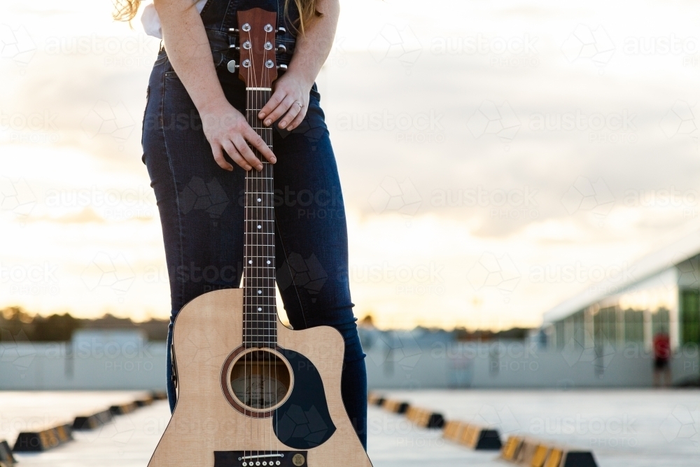 Young woman posing with guitar outside - Australian Stock Image