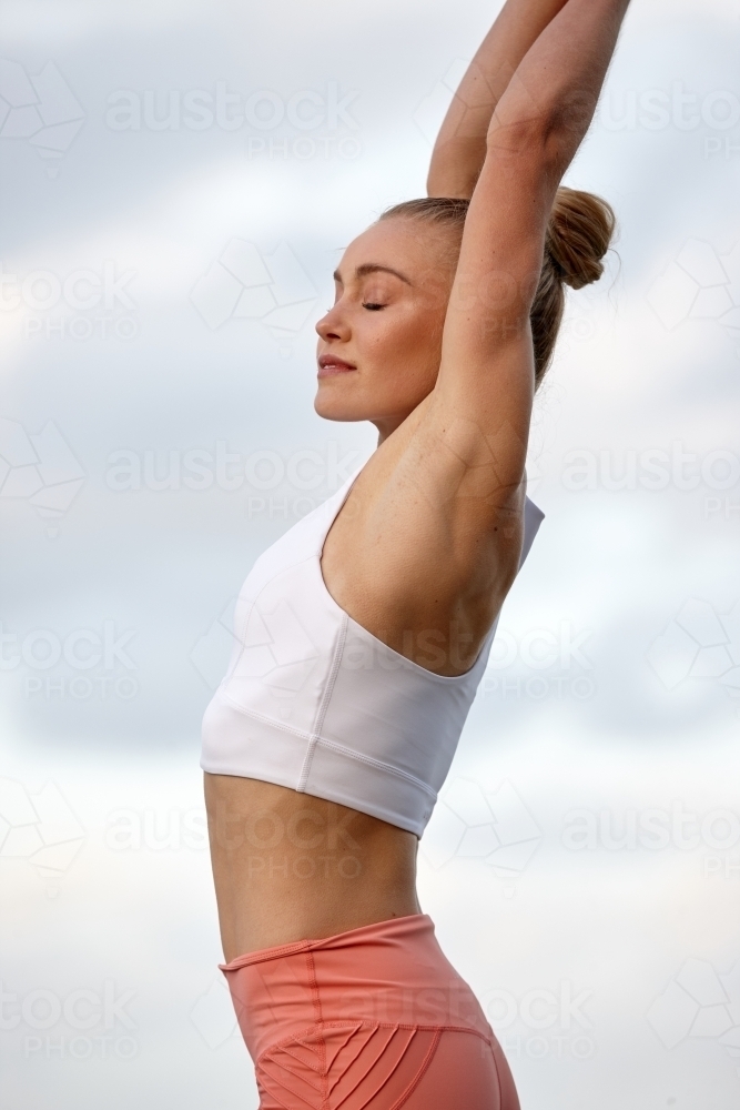 Young woman practising yoga by ocean - Australian Stock Image