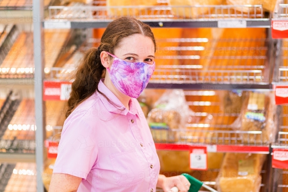 Young woman shopping for essentials like bread in grocery store during covid-19 pandemic - Australian Stock Image