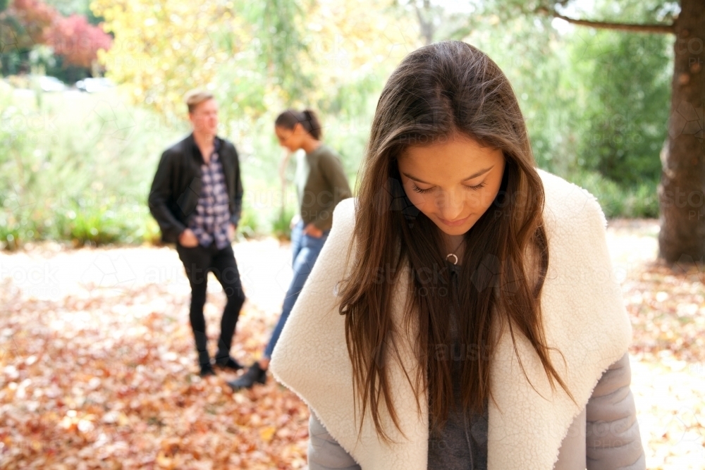 Young woman standing in front of other people in an outdoor setting - Australian Stock Image