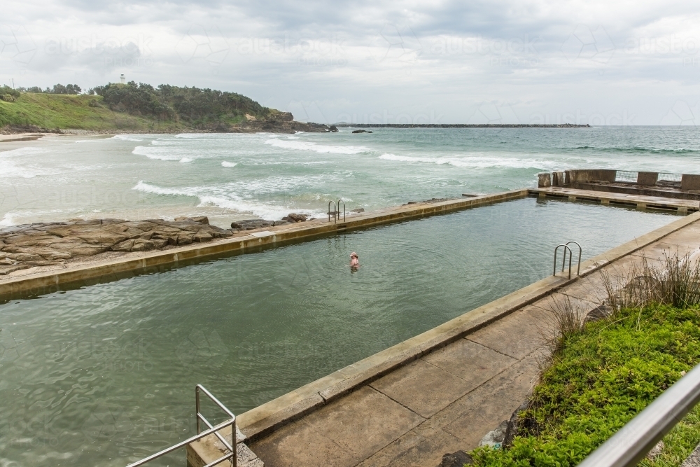 Young woman swimming in ocean bath at beach with ocean waves - Australian Stock Image