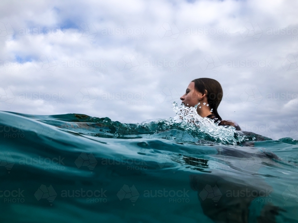 Young woman swimming in ocean on overcast day - Australian Stock Image