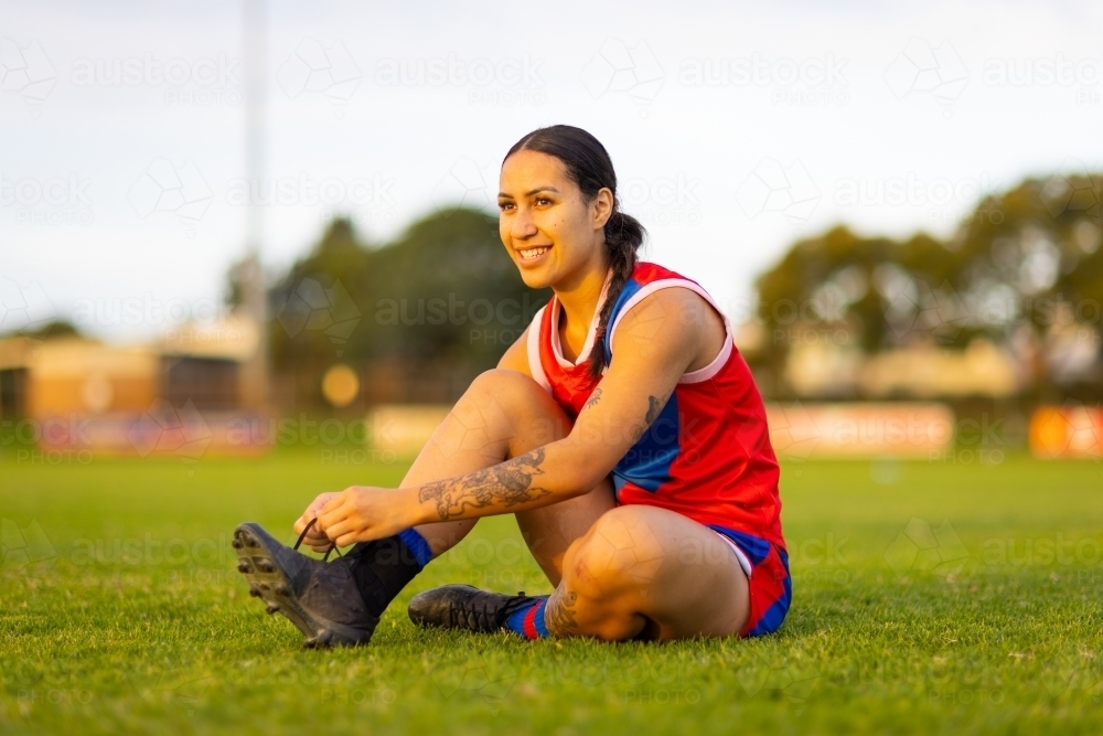 young woman tying football boot on playing field - Australian Stock Image