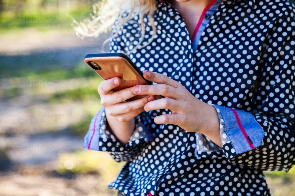 young woman using her mobile phone to keep connected to friends - Australian Stock Image