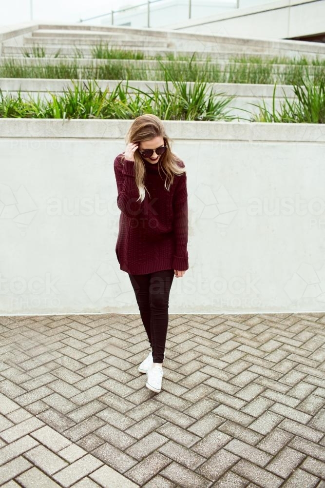 Young woman walking in city wearing sunglasses - Australian Stock Image