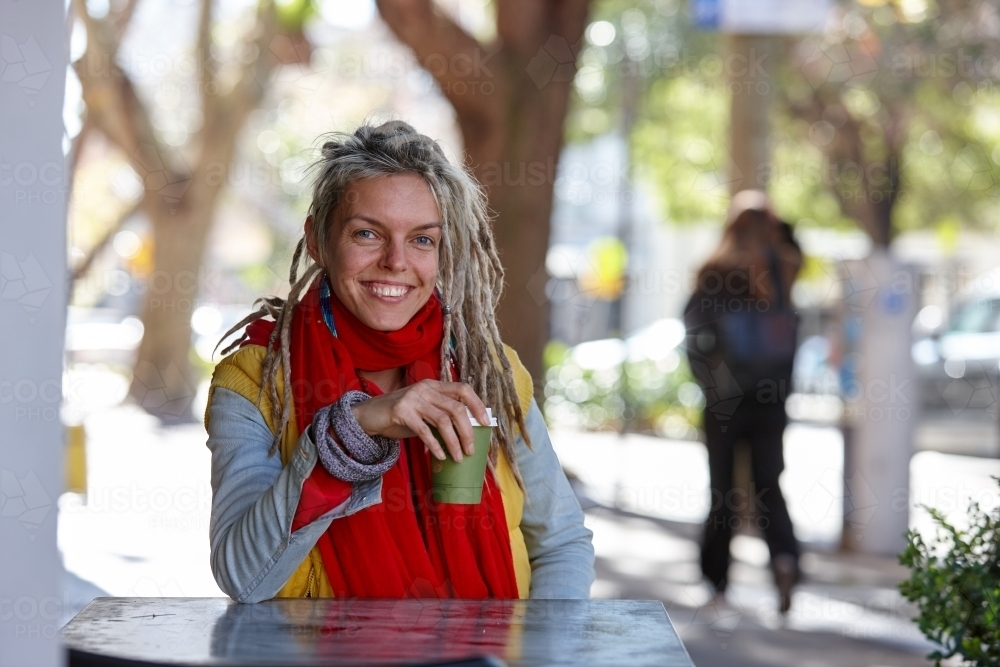 Young woman with dreadlocks smiling over coffee - Australian Stock Image