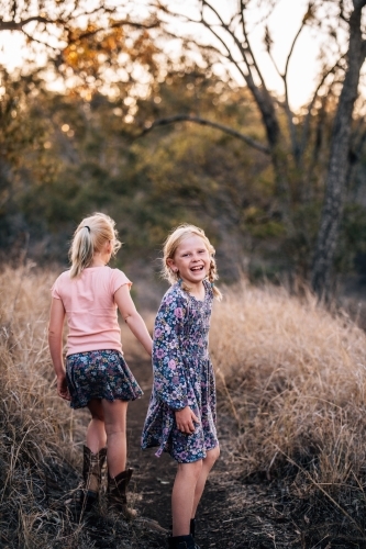 2 young girls walking down a dirt path