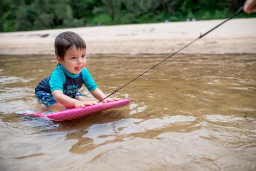 3 year old mixed race boy swims and plays in a river - Australian Stock Image