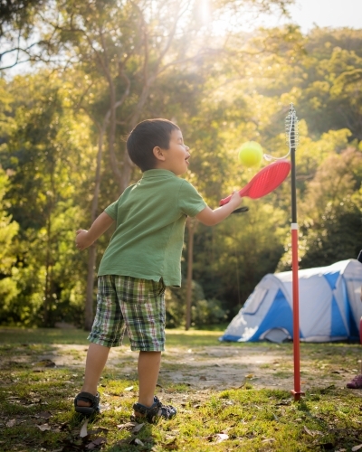 4 year old mixed race boy plays totem tennis on a camping trip - Australian Stock Image