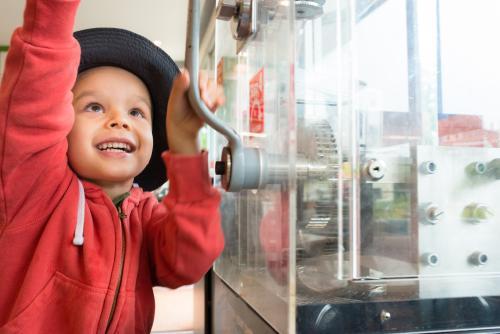 4 year old mixed race boy presses a souvenir penny at a local Sydney tourist attraction - Australian Stock Image