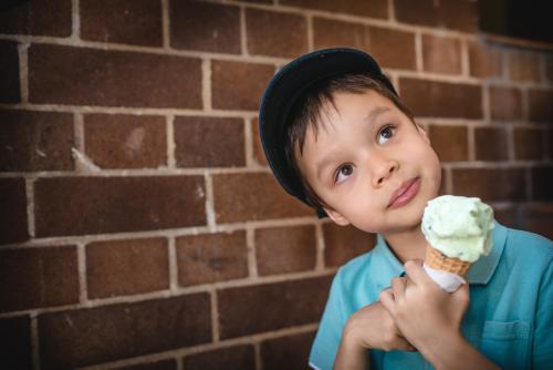 5 year old mixed race boy eating ice-cream on a warm summer day - Australian Stock Image
