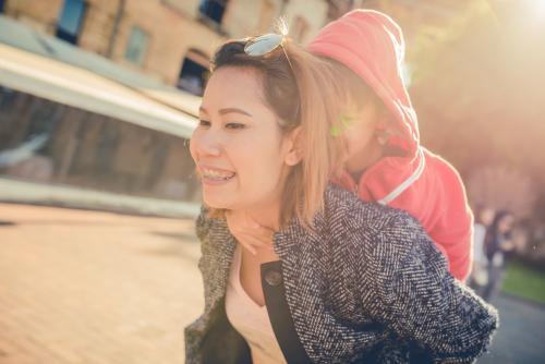 5 year old mixed race boy takes a piggy back ride with his Asian aunty on a tourist visit to Sydney - Australian Stock Image