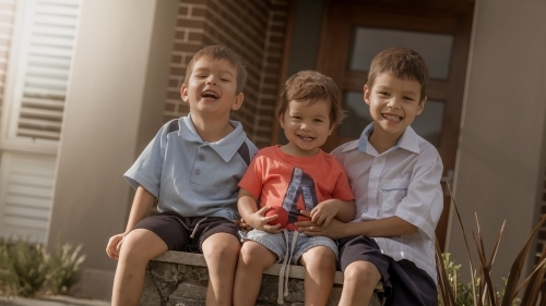 6 year old mixed race boy with his brothers leaves home for his first day of school - Australian Stock Image