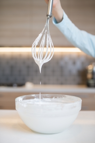 7 year old mixed race boy cooks at home with a whisk and bowl - Australian Stock Image