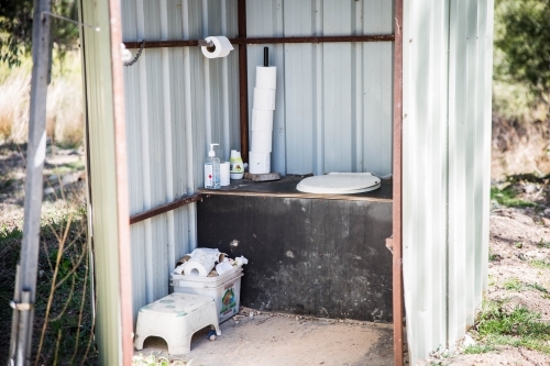 Tin outhouse with long drop toilet with toilet paper - Australian Stock Image