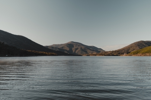 A blue lake with mountains in the background after sunrise