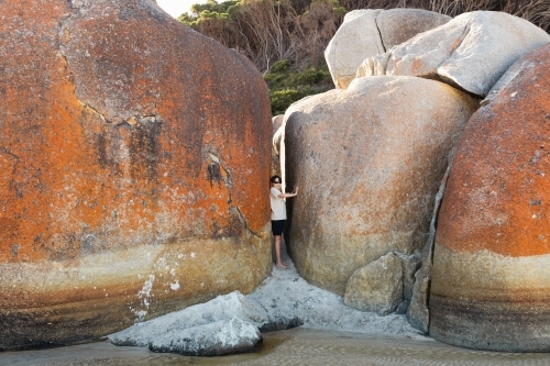 a boy child wearing sun glasses next to boulder rocks at Squeaky beach in Wilson's Promontory South - Australian Stock Image