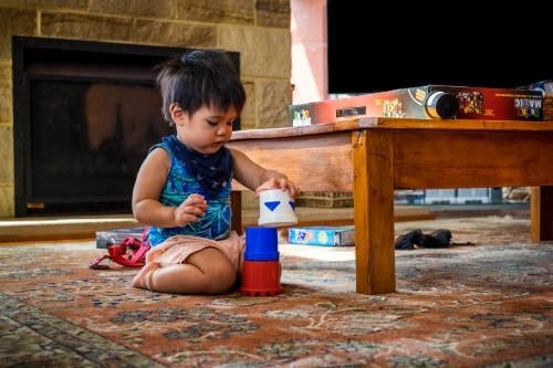 a boy toddler stacking cups on lounge room floor