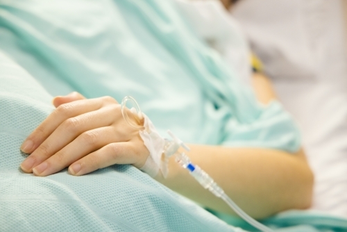 A cannula in the left wrist of a female patient lying on a bed - Australian Stock Image