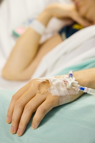 A cannula in the left wrist of a female patient lying on a bed - Australian Stock Image