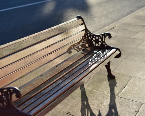 A classic wooden public bench in the afternoon sun - Australian Stock Image