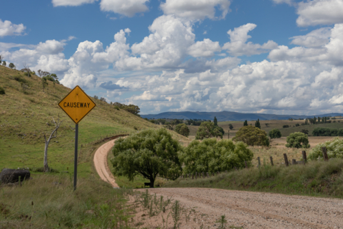 A cloudy sky, a causeway sign and a country road - Australian Stock Image