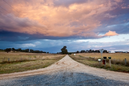 A country road leads off into the distance an under storm clouds - Australian Stock Image