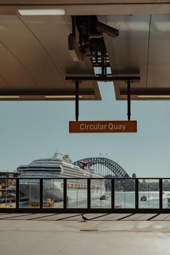 A cruise ship sits in front of the Harbour Bridge as seen from Circular Quay Train Station - Australian Stock Image