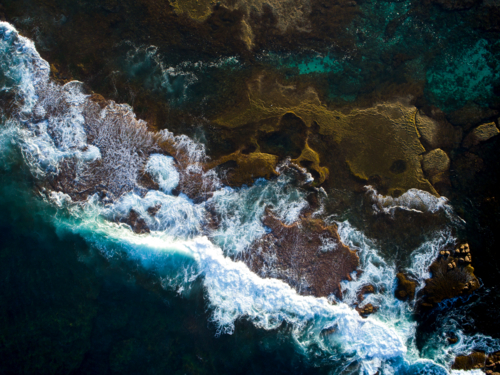 A dark ocean crashes over an exposed reef bed - Australian Stock Image