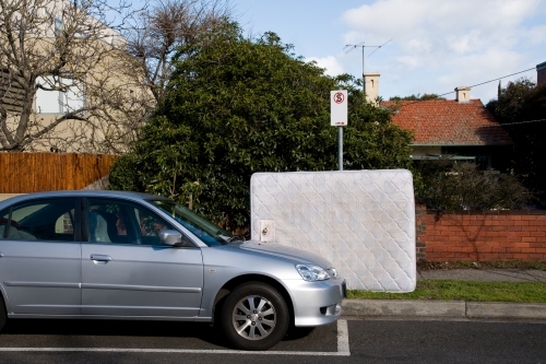 A discarded mattress resting against a no standing sign - Australian Stock Image