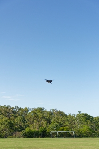 A drone, or UAV, or RPAS hovering over a football field - unmanned aerial vehicle - Australian Stock Image