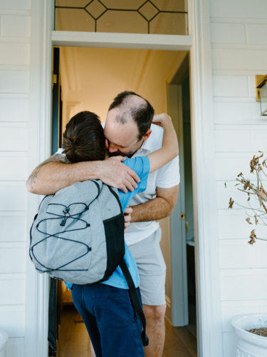 A father embracing his son in the doorway. - Australian Stock Image